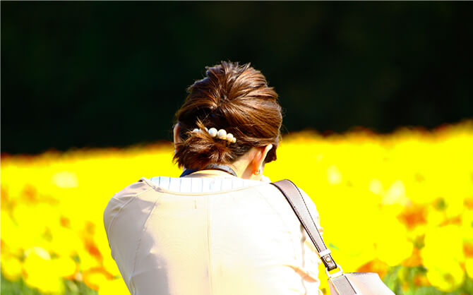 悩んでいる女性と花畑の写真